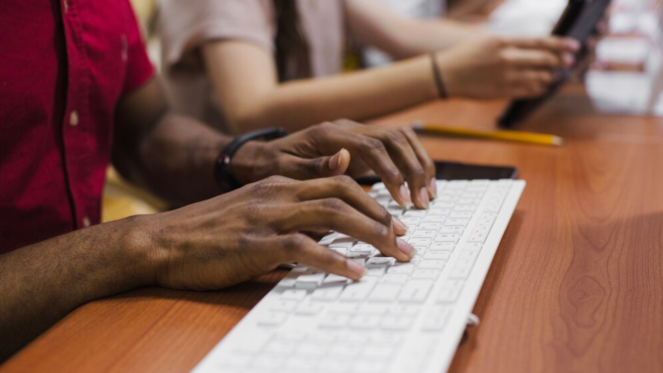 Adultos de várias etnias, em formação escrevem em teclado de computador