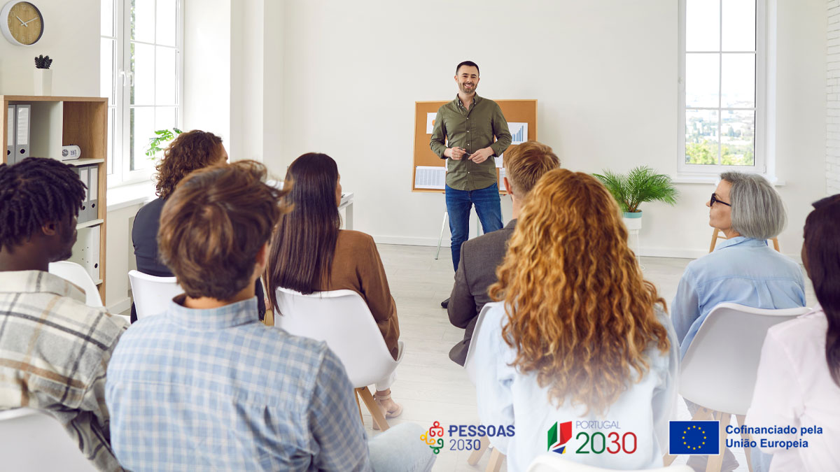 sala de formação com formador e pessoas sentadas a assistir