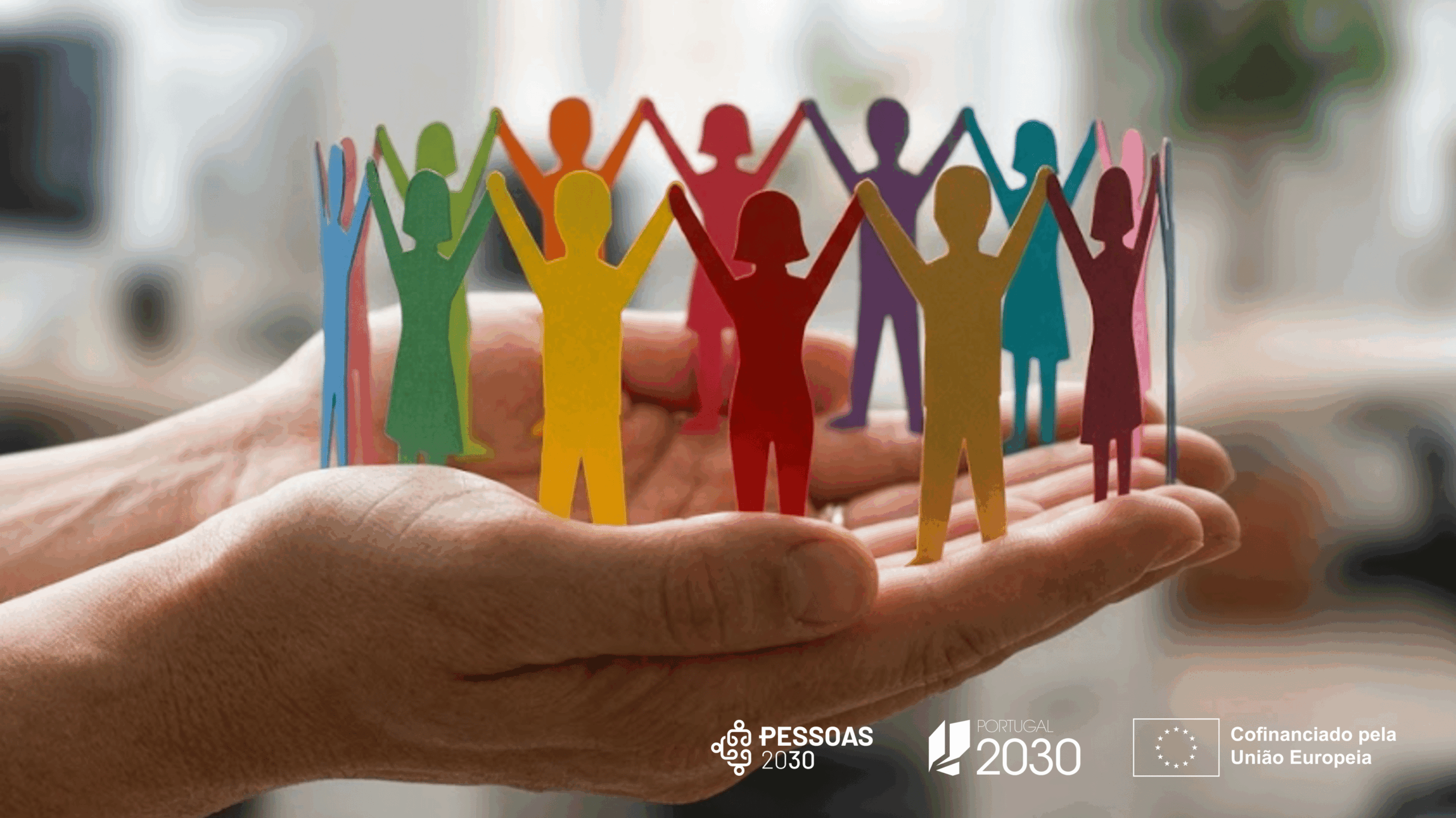 Regulamento Específico da Área Temática Demografia, Qualificações e Inclusão mãos em forma de concha a segurarem uma roda de figuras coloridas em papel. barra de cofinanciamento do PESSOAS 2030